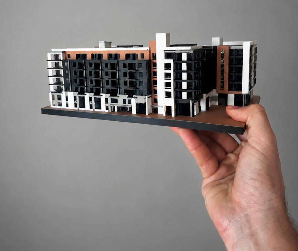 3D-printed multicolor scale model of a 7-story mixed-use apartment complex, showing full facade detail, balconies, and recessed window openings, printed from the project's real Revit model