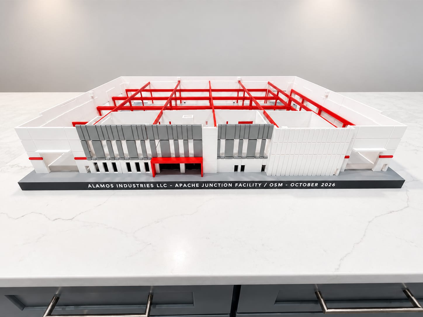 Front elevation of a 3D-printed industrial facility model on a marble counter, project name on the base