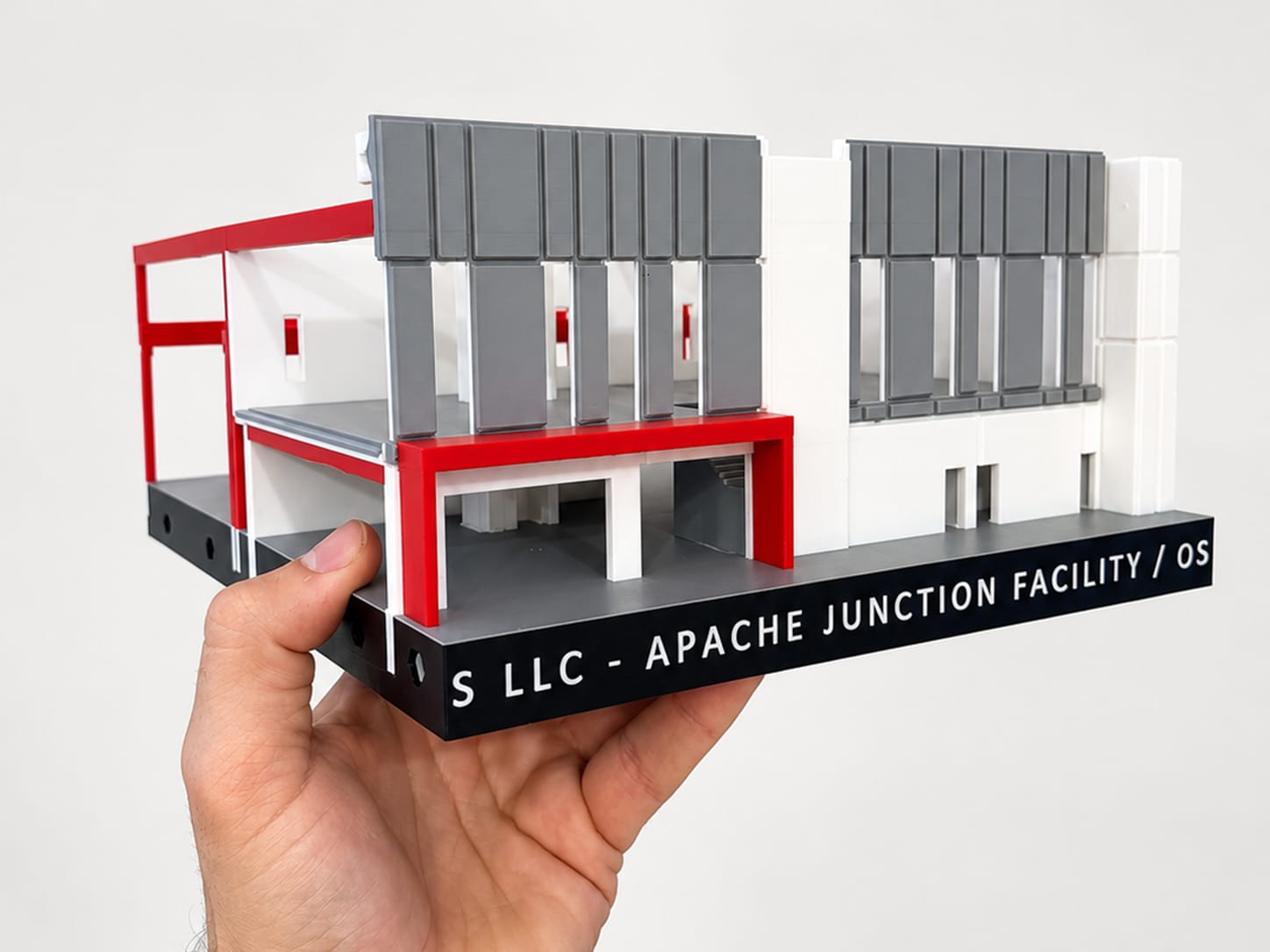 One printed section held in a hand: office front with grey panels and a red entry canopy